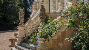 Una imponente escalera con barandillas ornamentadas, un dosel de hierro forjado y una estatua.