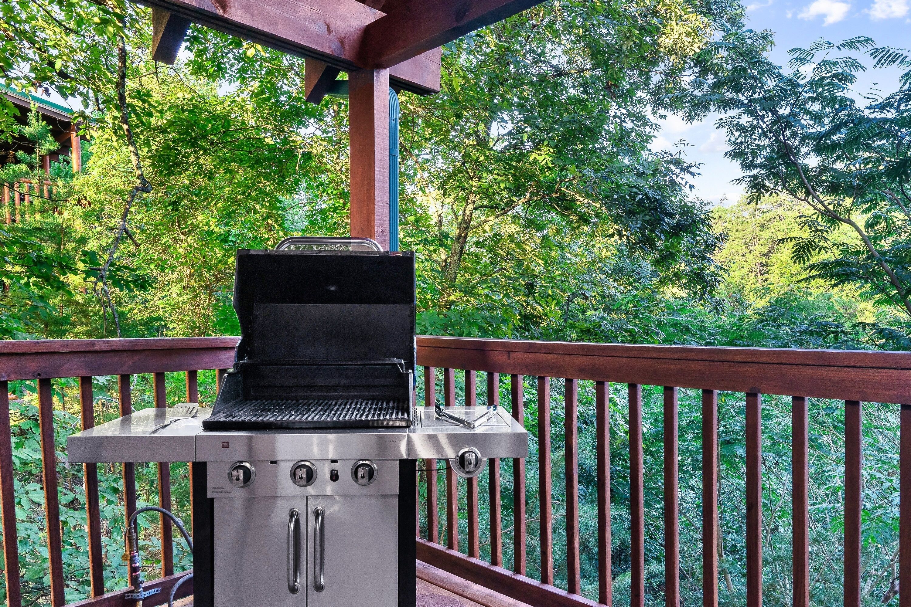 Una parrilla en una terraza de madera con vistas a exuberante vegetación.