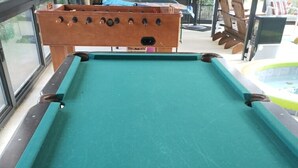 Un tavolo da biliardo con struttura in legno e superficie rivestita in feltro verde.