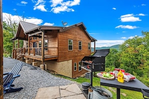 A wooden cabin with a deck, outdoor grill, and seating area.