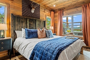 A bedroom with a bed, bedside tables, and a window with curtains.