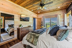 Un dormitorio de cabaña de madera con cama, cómoda y un amplio ventanal que ofrece una vista panorámica.