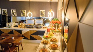 Montaje de bufé con diferentes opciones de comida y un comedor con sillas y mesas.