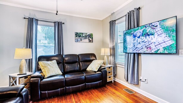 A living room with a leather sofa, two side tables with lamps, a flat-screen TV, and a framed picture on the wall. - Rivers Edge: Spacious, Riverwalk, Close to USC, Ft Jackson, all area Hospitals (West Columbia)