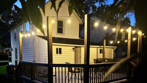 A two-story house with a deck, string lights, and a wooden fence. - Rivers Edge: Spacious, Riverwalk, Close to USC, Ft Jackson, all area Hospitals (West Columbia)