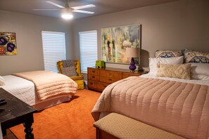 A bedroom with two beds, a dresser, a chair, and artwork on the walls.