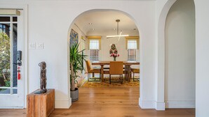 A dining area with a wooden table, chairs, and a vase of flowers.