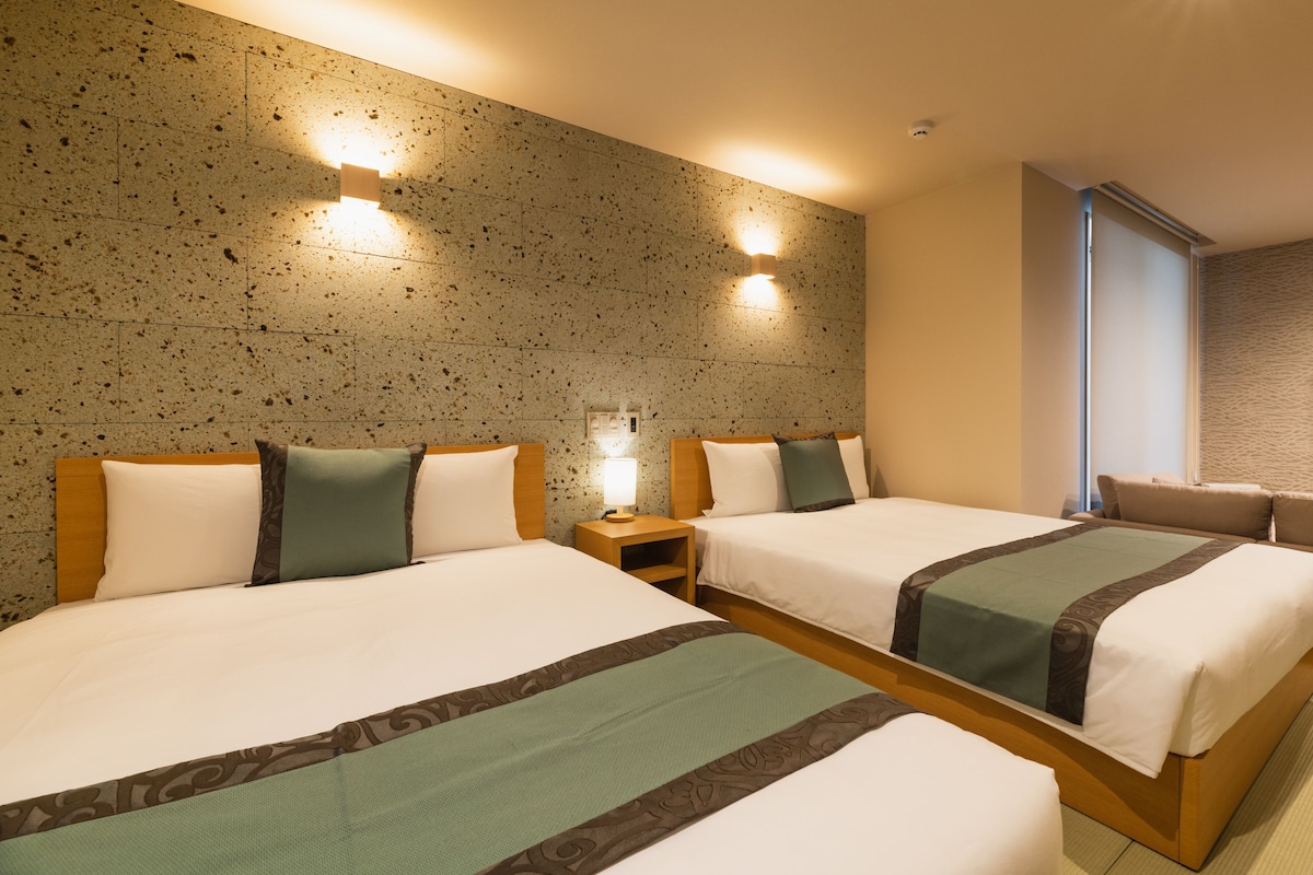 Una camera d'hotel con due letti, un muro in pietra e una finestra con vista.