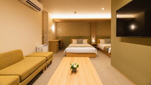 A hotel room with a bed, a sofa, a TV, and a small table with a plant. - GRAND BASE Nagasaki Nakamachi (Nagasaki)