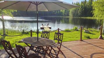 Una terraza al aire libre con una mesa y sillas, con vista a un lago.