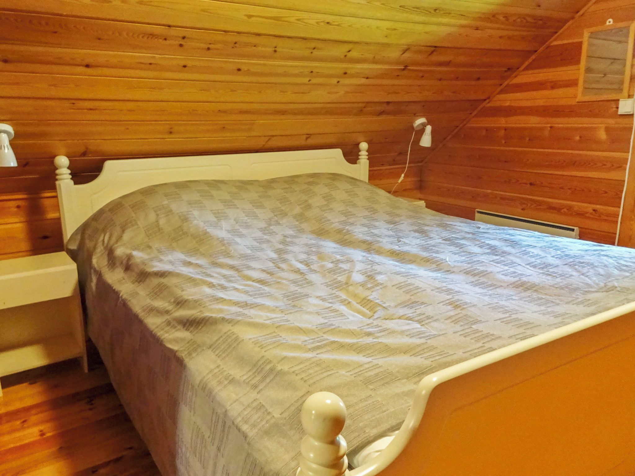 A single bed in a room with wooden walls and a sloped ceiling.
