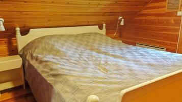 A single bed in a room with wooden walls and a sloped ceiling.