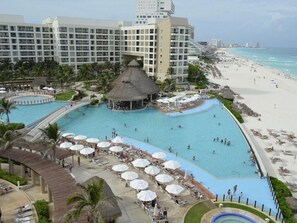 A resort with a large pool, beach, and hotel buildings.