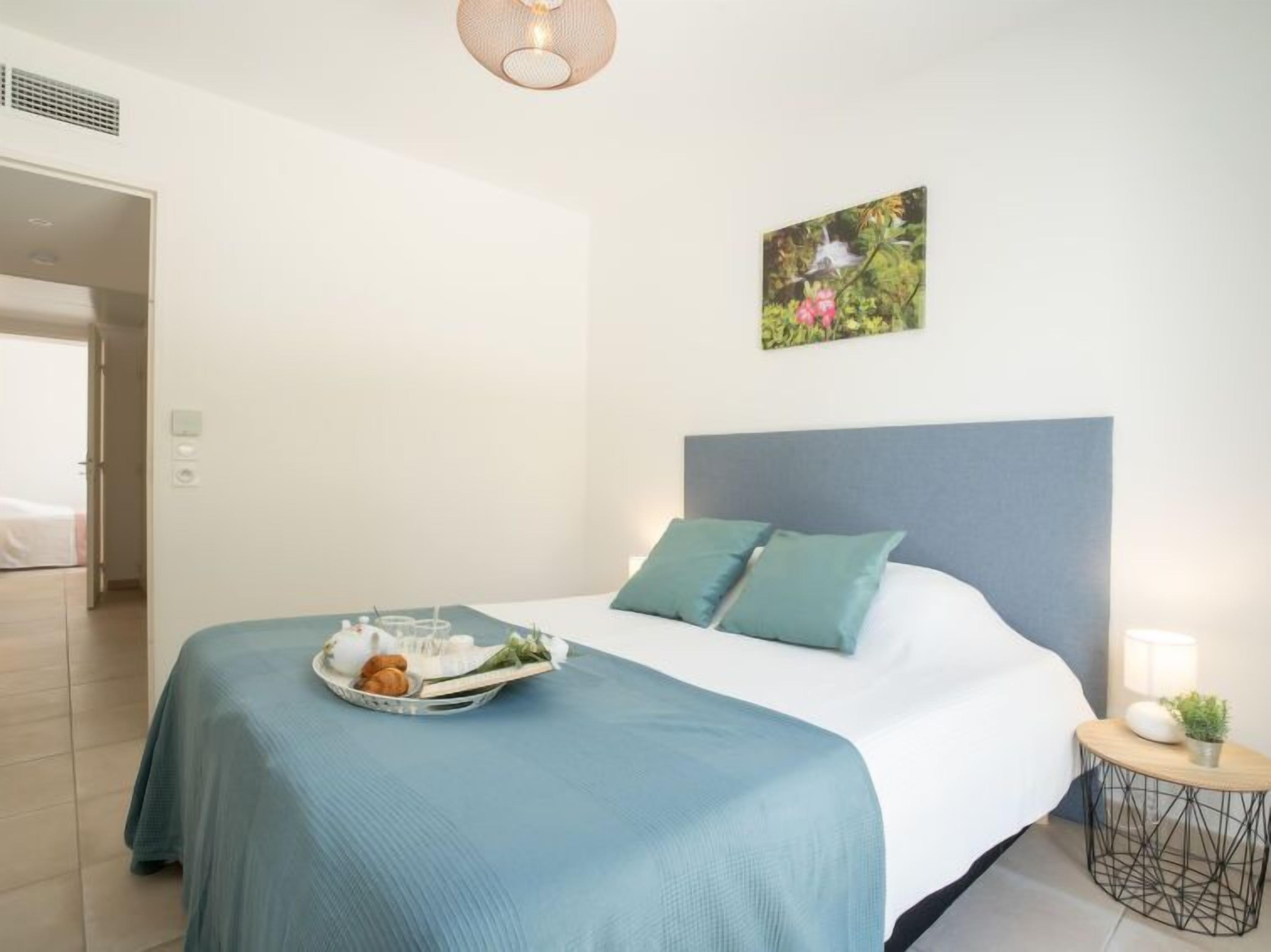 Une chambre à coucher moderne avec un lit, une table de chevet dotée d’une lampe et un tableau accroché au mur.