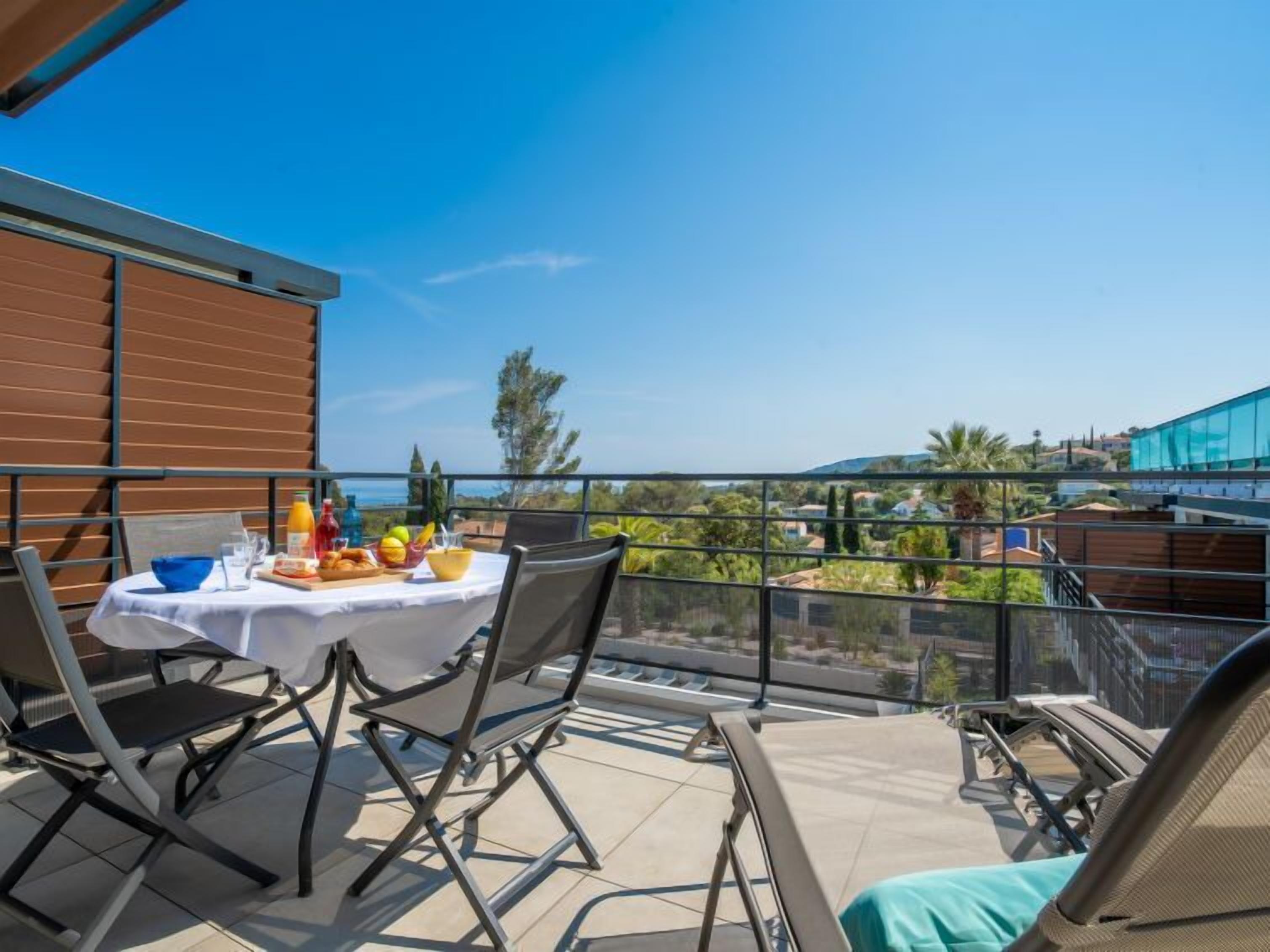 Een balkon met een eettafel, stoelen en uitzicht op het omliggende landschap.