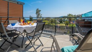 En balkon med et bord dækket til et måltid, stole og udsigt over det omkringliggende landskab.