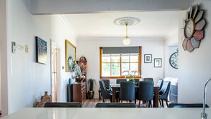 Un coin repas avec une table blanche, des chaises noires et une fenêtre donnant sur un paysage verdoyant.