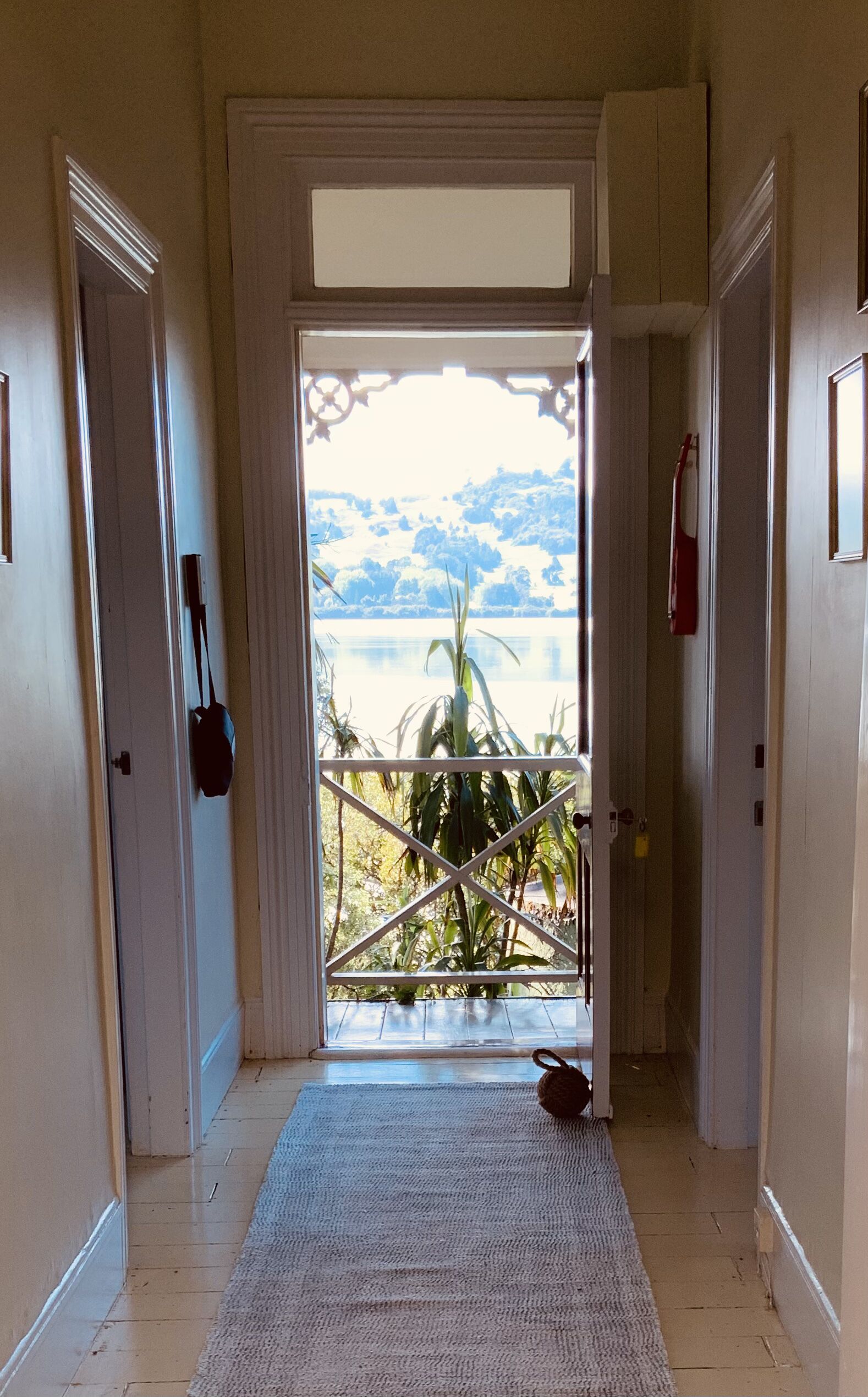 A hallway leading to a door with a view of a lake and mountains.
