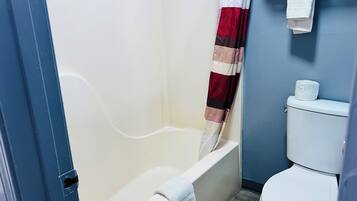A bathroom with a bathtub, toilet, and a shower curtain.