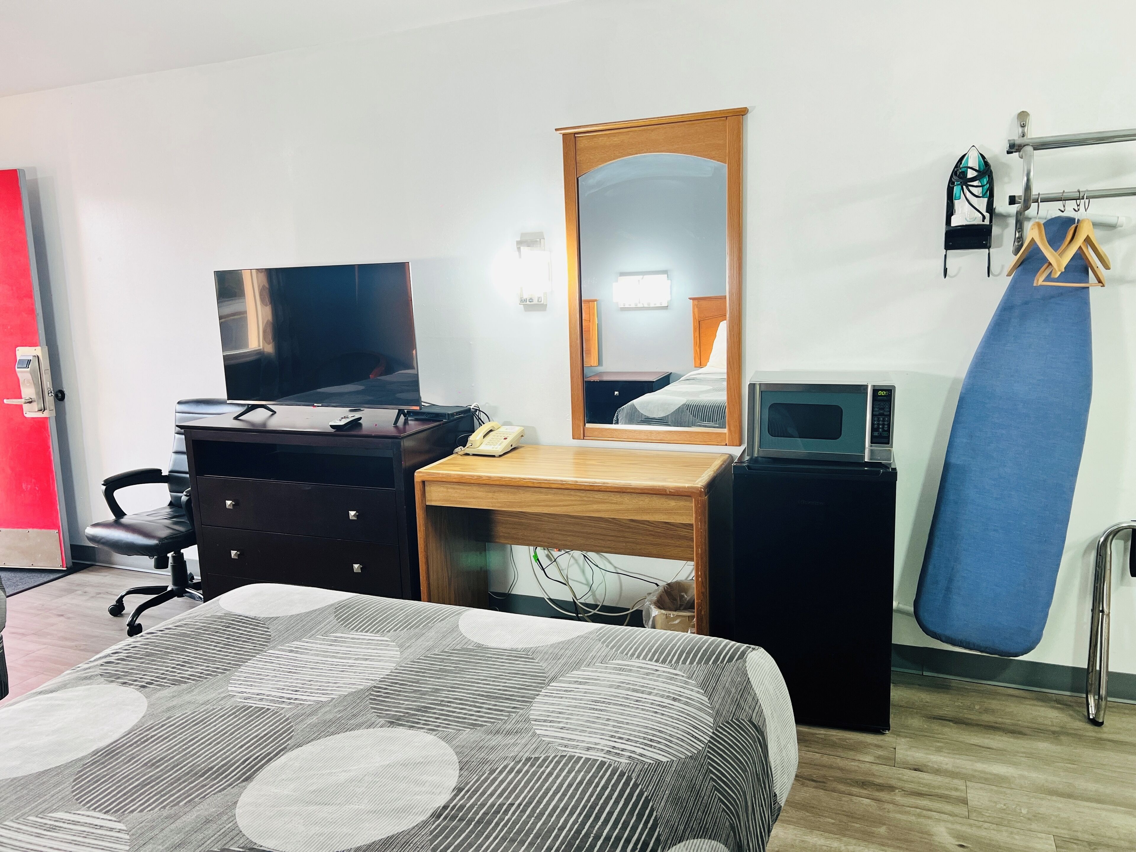 Hotellihuone, jossa on sänky, kirjoituspöytä peilillä, televisio, puhelin, mikroaaltouuni ja nyrkkeilysäkki.