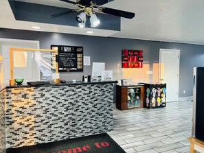 A reception area with a check-in counter, a bulletin board with information, and a decorative wall piece.