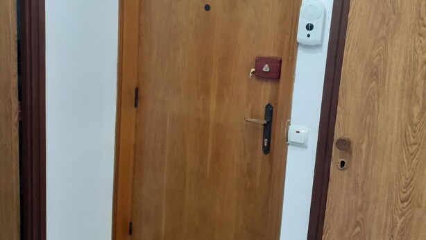 A wooden door with a small window above it, a doorbell, and a sign indicating an exit. - 2-Bedroom Apartment in Bucharest near town center (Bucharest)