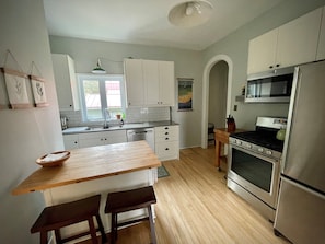 Enjoy cooking in this well-equipped kitchen with a stainless steel refrigerator, oven, and microwave.