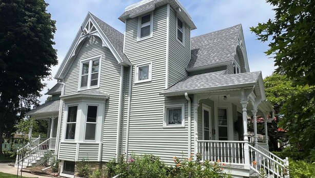 A large, two-story house with a wrap-around porch, multiple windows, and a steeply pitched roof. - Updated Victorian in the Heart of Sheboygan. Beach, Downtown, Golf, Road America (Sheboygan)