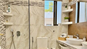 A modern bathroom with a glass-enclosed shower, a toilet, and a vanity with a sink and mirror. - Villasonboard 3 Bedroom Penthouse Vouliagmeni (Vouliagmeni)