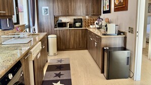 A compact kitchen with wooden cabinets, a microwave, a coffee maker, and a refrigerator. - Villasonboard 3 Bedroom Penthouse Vouliagmeni (Vouliagmeni)