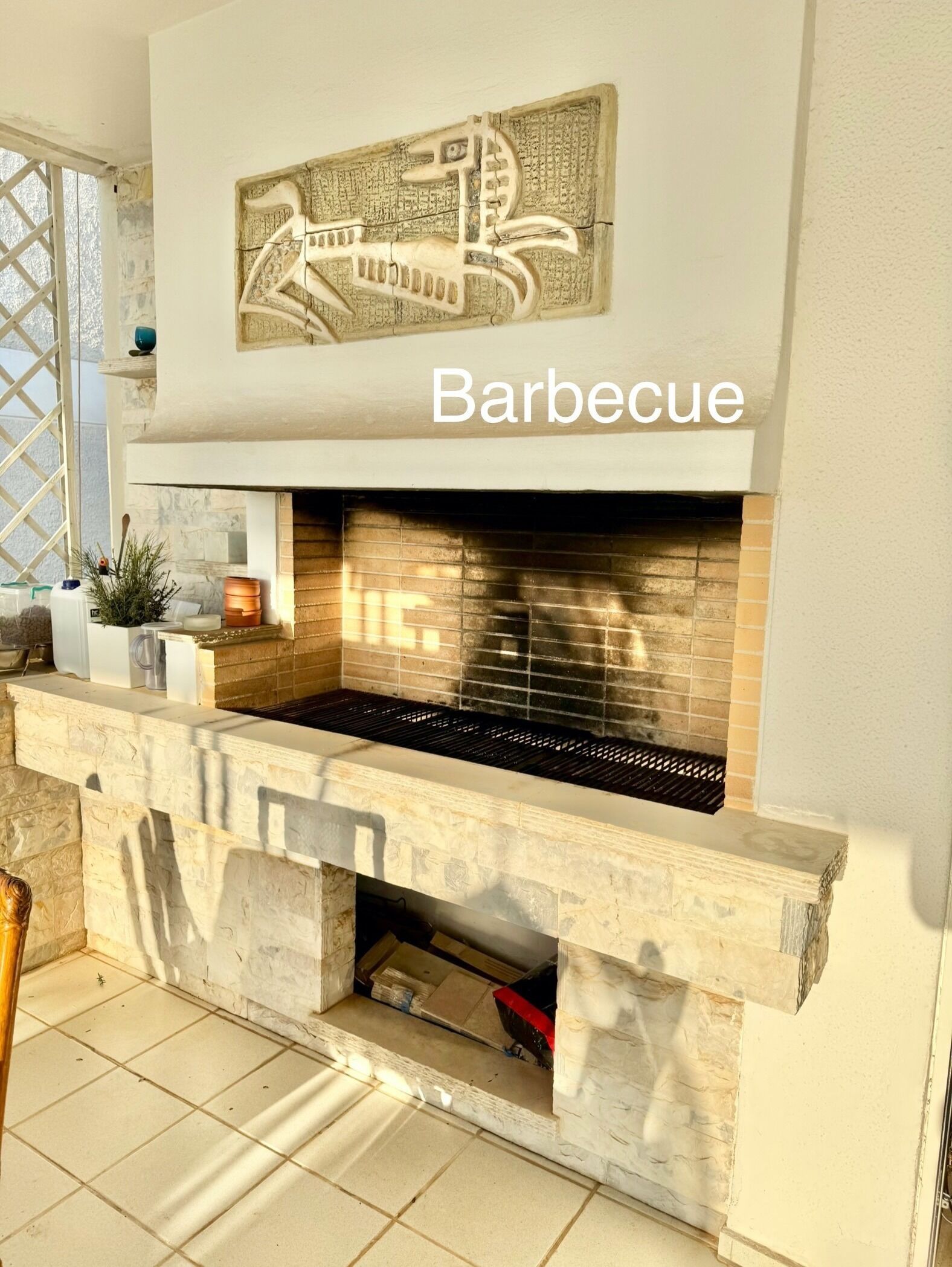 Ein Grillbereich mit gefliestem Rückspritzschutz, einer Steinstruktur und einer dekorativen Karte über dem Grill.