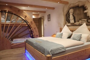 Ein Schlafzimmer mit einem Holzbett, einer großen Holzradkonstruktion und einem Bild an der Wand.
