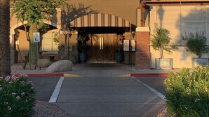 The entrance to Twisted Grove Parlor Bar, featuring a brown facade, arched entrance, and potted plants. - Heart of Scottsdale (Scottsdale)