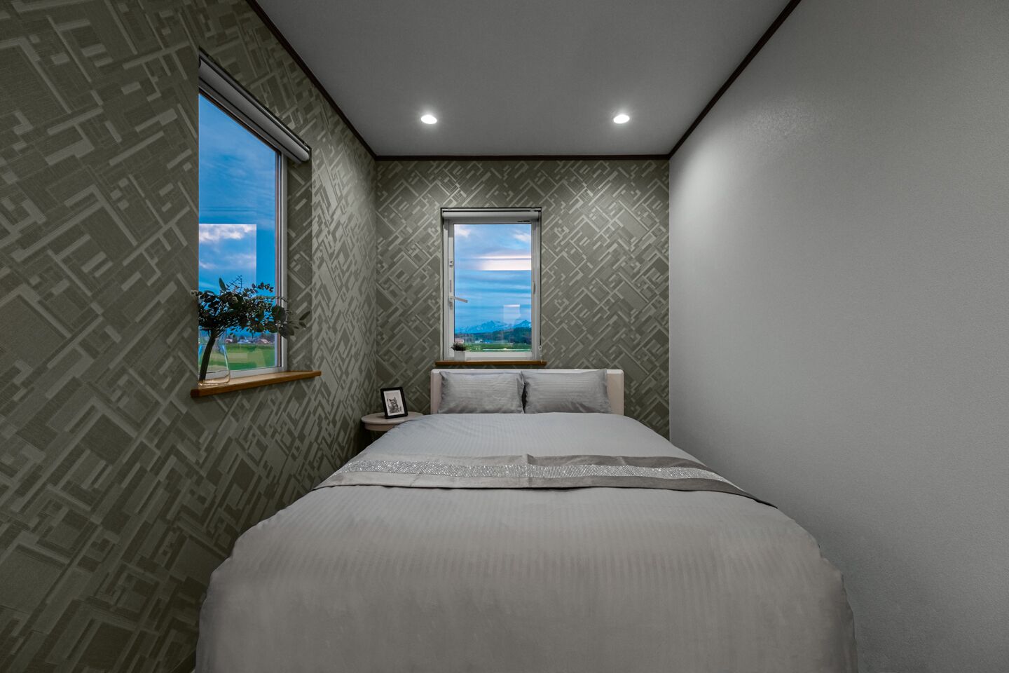 A bedroom with a large bed, two windows, and patterned wallpaper.
