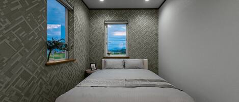 A bedroom with a large bed, two windows, and patterned wallpaper.