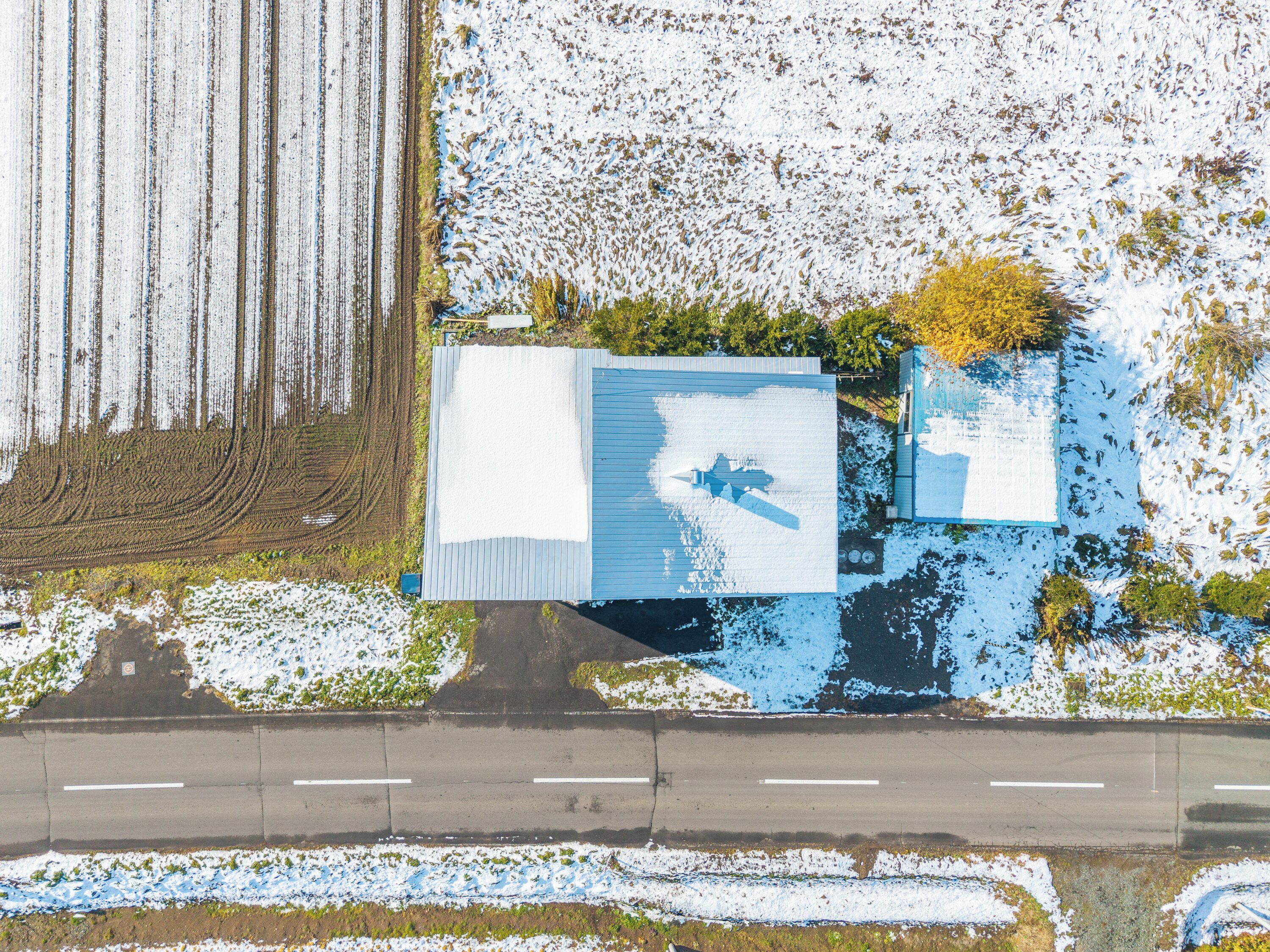 An aerial view of a building with a large white roof and a blue section.