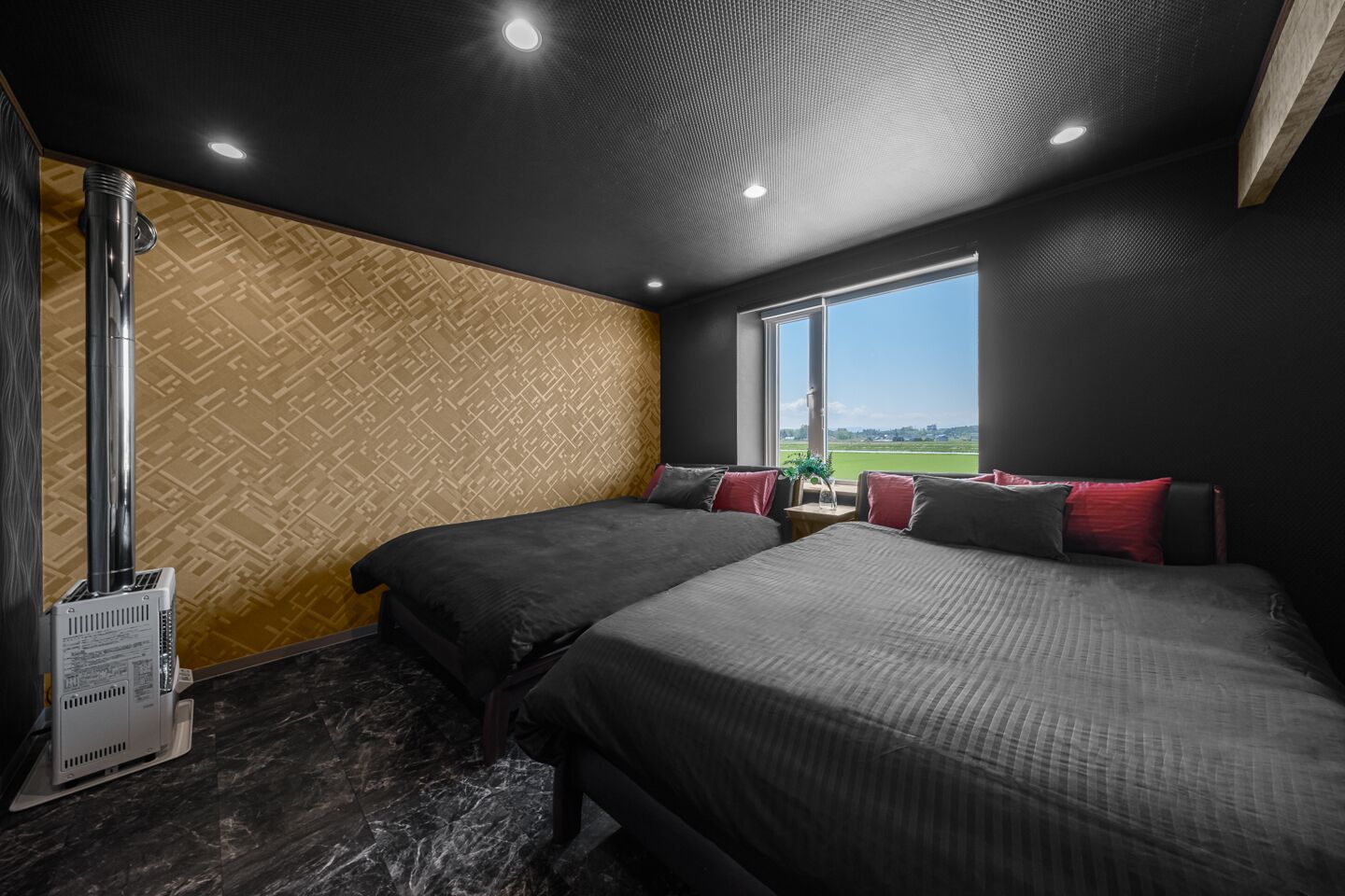 Une chambre d’hôtel avec deux lits, une grande fenêtre donnant sur un champ verdoyant et une cheminée.