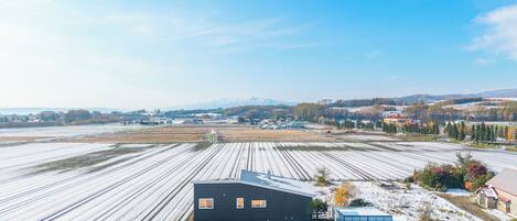 En stor, industriel bygning med fladt tag, omgivet af sneklædte marker og en klar himmel.
