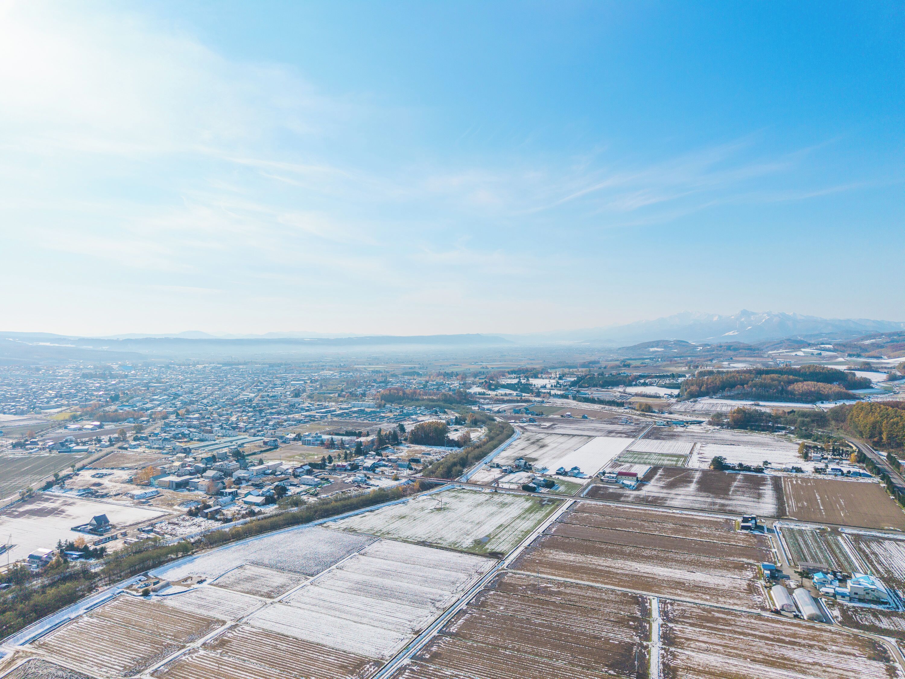 An aerial view of a town with residential areas, agricultural fields, and industrial buildings.