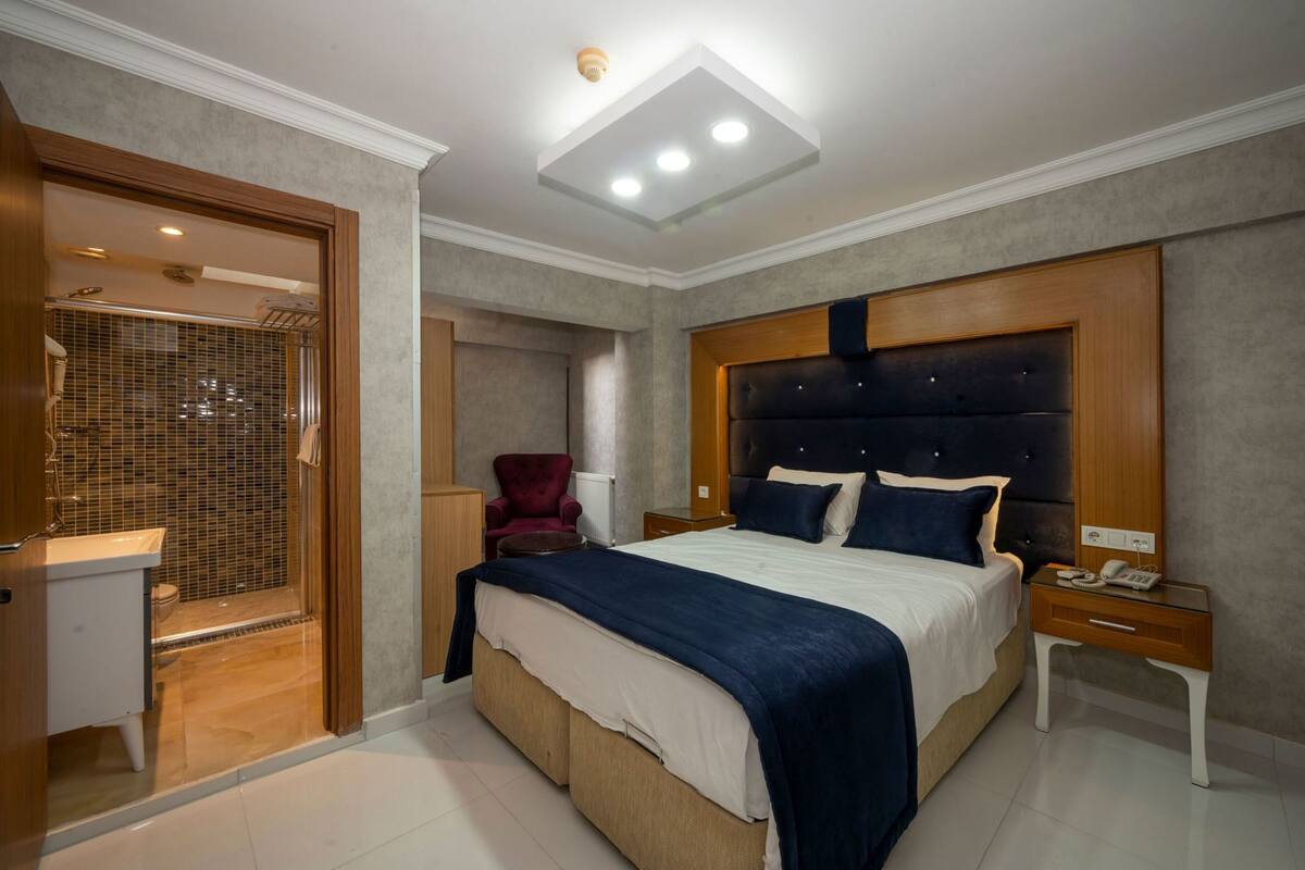 A bedroom with a bed, a bedside table with a phone, a chair, and a walk-in closet.