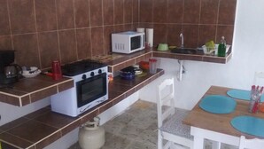 Une cuisine de taille réduite équipée d’une cuisinière à gaz, d’un four à micro-ondes et d’un petit évier.