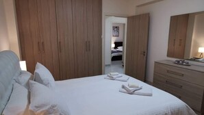 A bedroom with a bed, a wardrobe, a dresser, and a mirror. - Spacious Boutique Apartment (Larnaca)