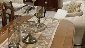 A living room with a sofa, a dining table with a glass centerpiece, a television on a stand, and a wooden cabinet. - Spacious Boutique Apartment (Larnaca)