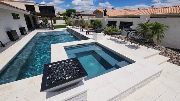 Piscina retangular com lareira embutida, rodeada por um terraço com assentos e plantas.