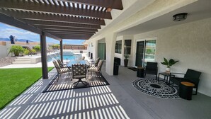 Um alpendre coberto com piscina, mobiliário de exterior e vista para as montanhas.