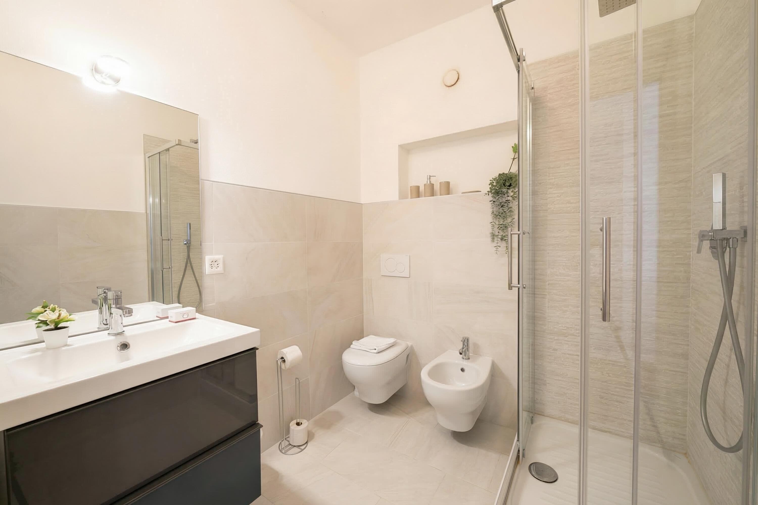 A modern bathroom with a glass-enclosed shower, a white sink with a mirror, and a toilet.