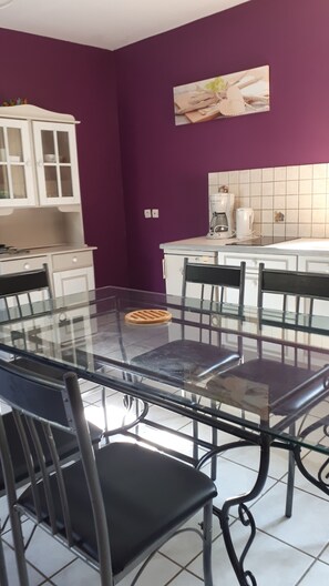 Ein Essbereich mit einem Glastisch und Stühlen, weißen Schränken und einer violetten Wand.