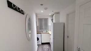 A narrow hallway with a washing machine, a refrigerator, and a sink in the background. - Charming 1-bed Apartment in Coventry (Coventry)