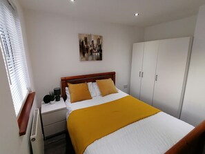 A bedroom with a bed, a nightstand, a wardrobe, and a painting on the wall. - Charming 1-bed Apartment in Coventry (Coventry)