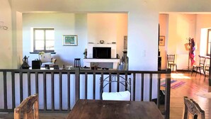 Un vaste espace de vie comprenant une cheminée, un téléviseur et une table à manger avec des chaises.